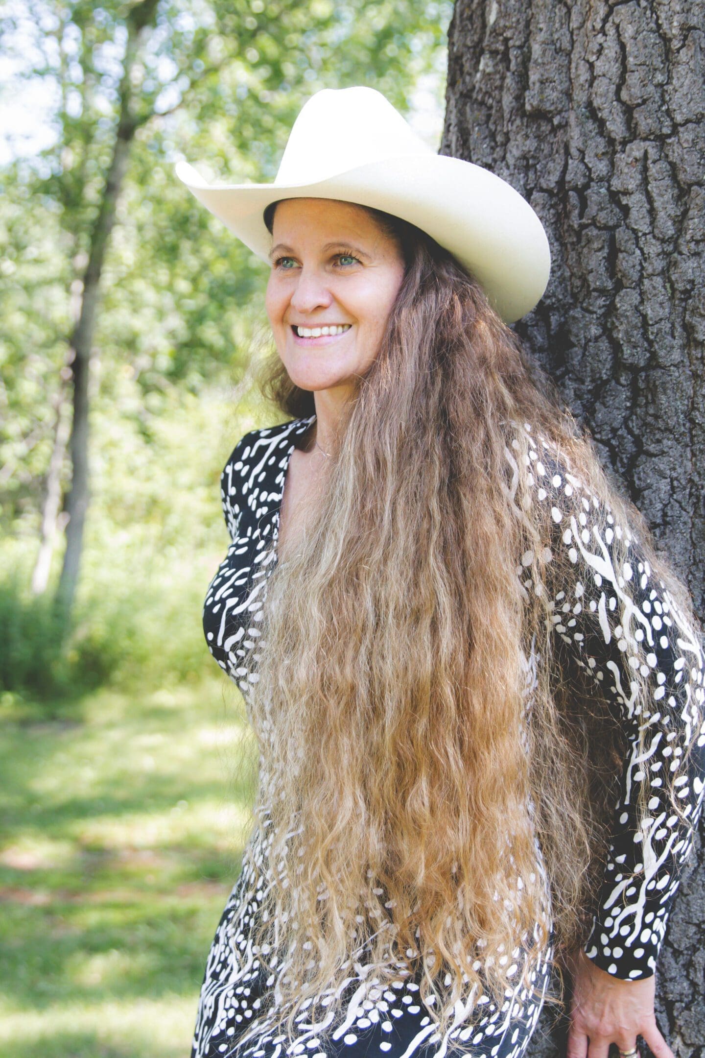 Woman with long hair wearing a white hat outdoors.