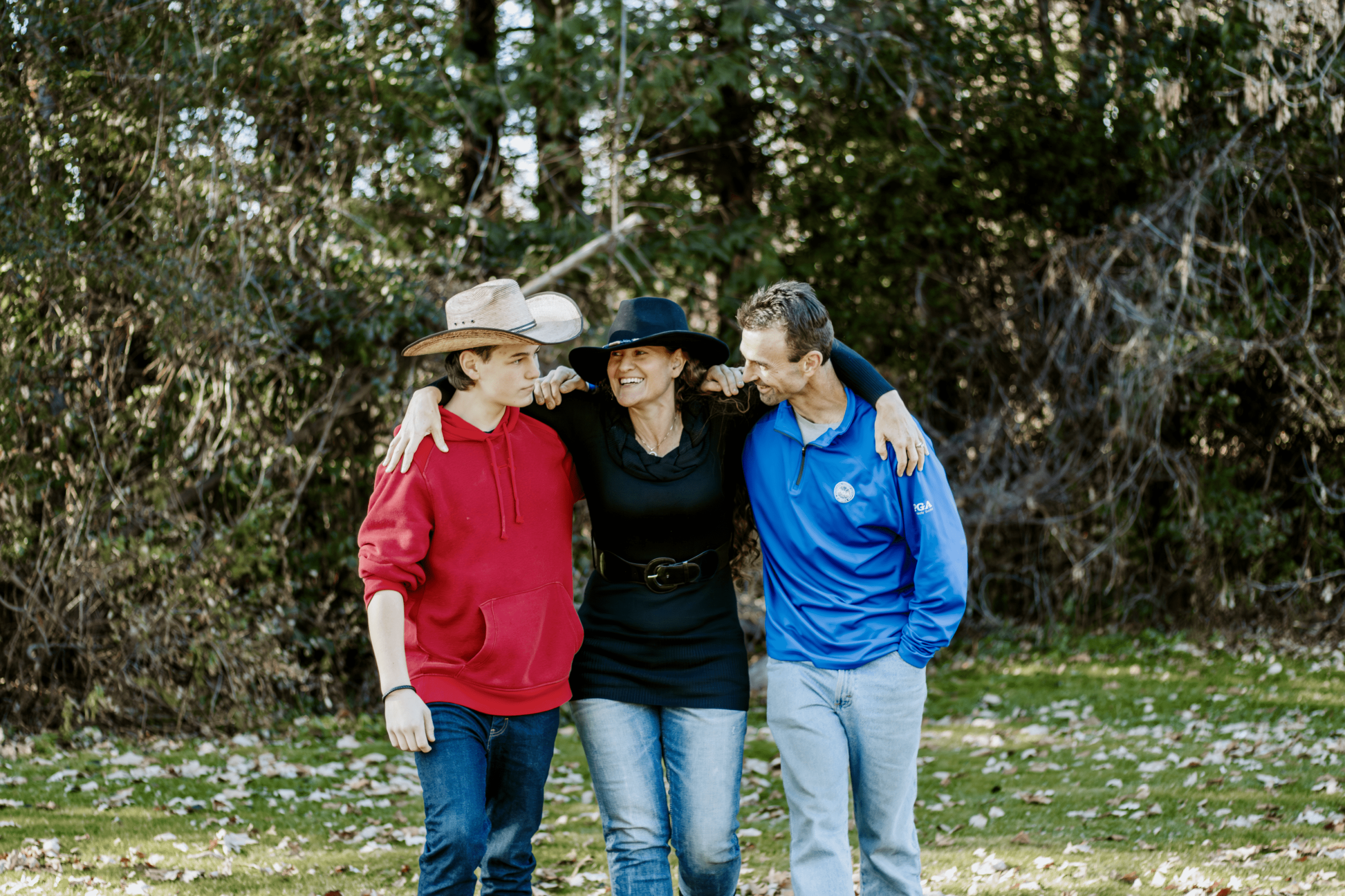 Three friends stand closely together outdoors, smiling and enjoying each other's company.